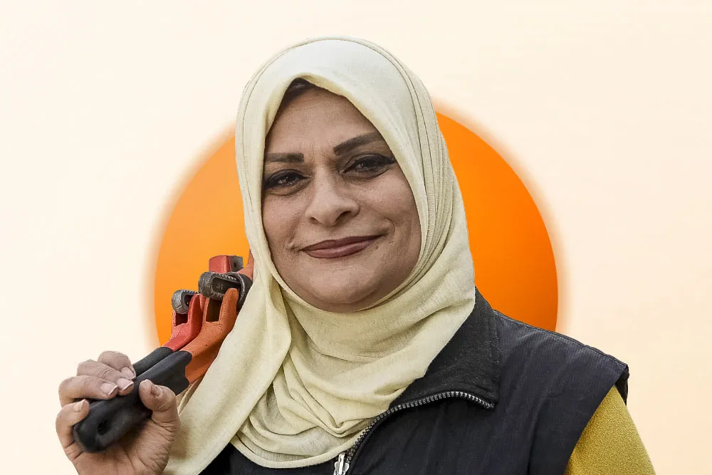 A portrait of a Jordanian woman wearing a headscarf and resting a wrench against her shoulder.