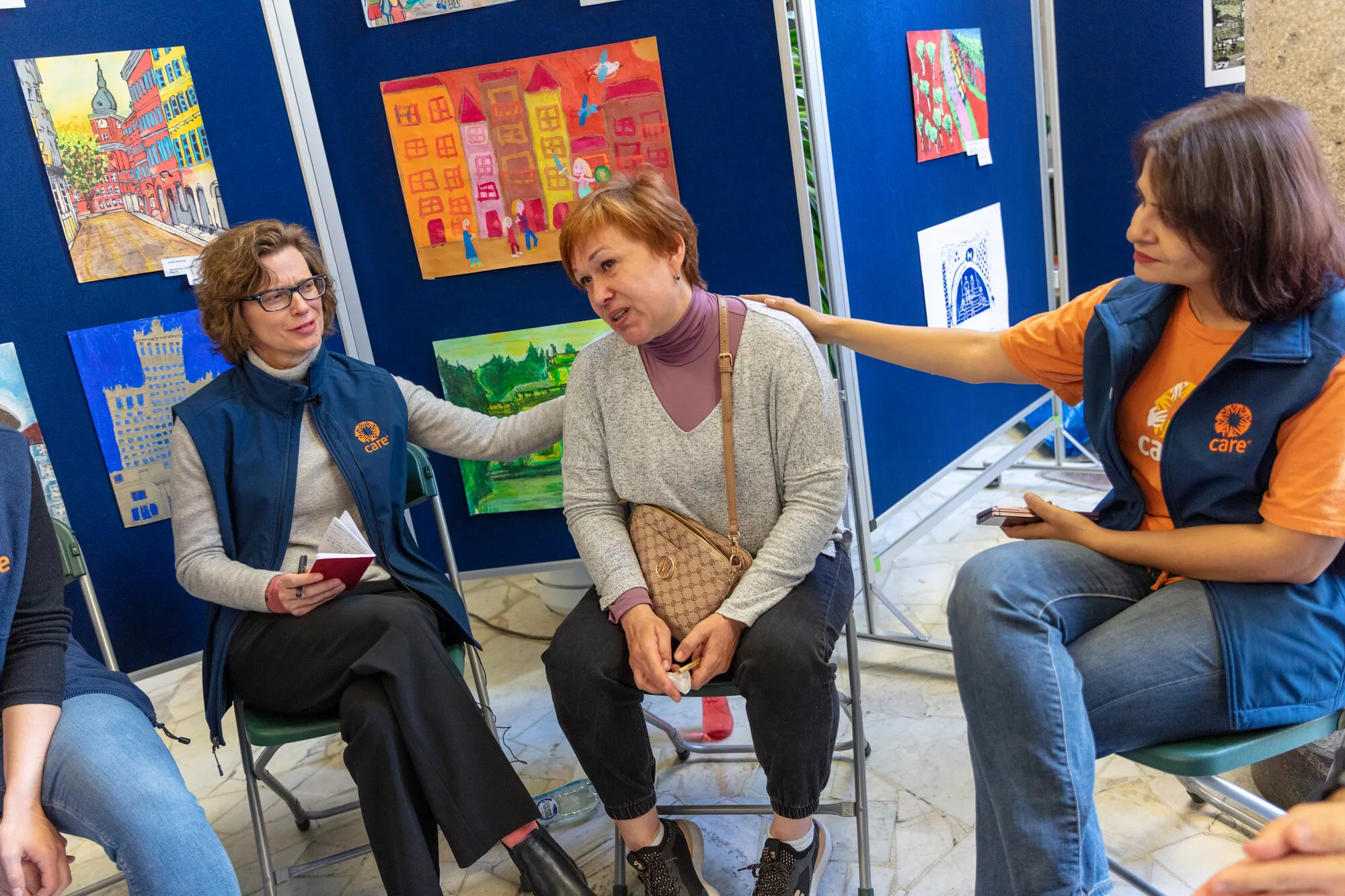 CARE President and CEO Michelle Nunn (left) and Deepmala Mala, CARE VP for Humanitarian Affairs, comfort Liudmyla Staston, a Ukrainian teacher, who just recieved certification in Poland to teach the refugee kids